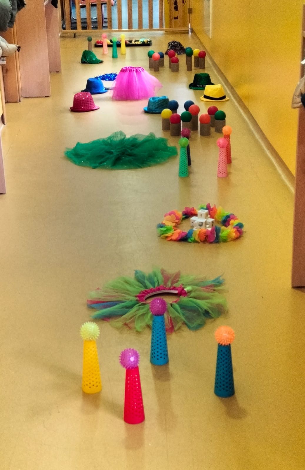 Pasillo de la escuela infantil decorado con tutús, sombreros de colores y conos con pelotas sensoriales.