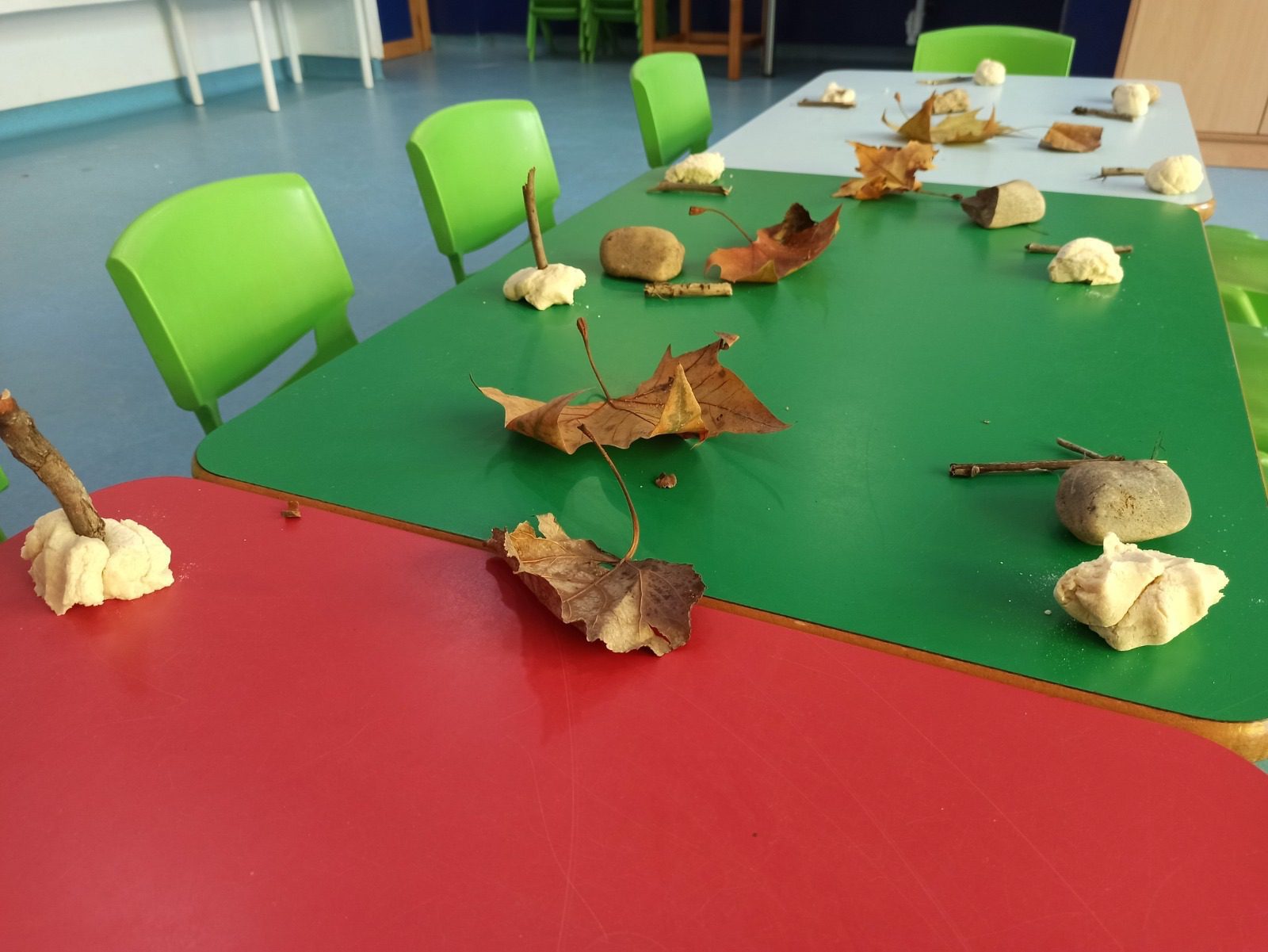 Mesa de aula con pan, piedras, palos y hojas secas de otoño.