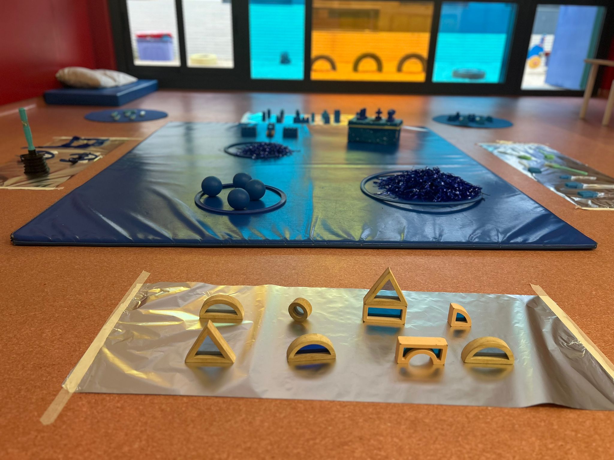 Bloques de madera con centros de acrílico azul dispuestos sobre papel de aluminio en un aula.
