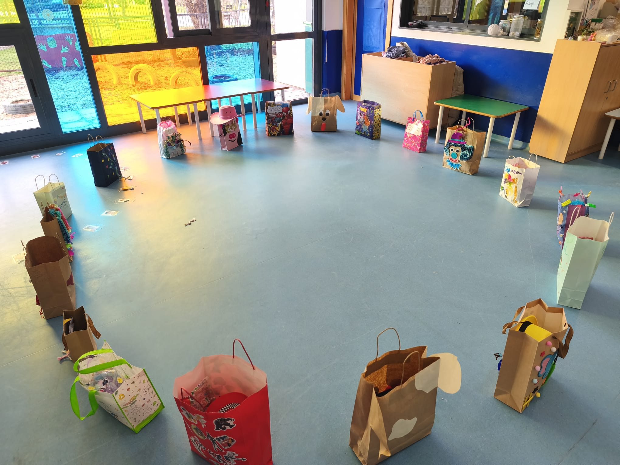 Aula de educación infantil con bolsas de papel decoradas colocadas en círculo para la actividad de carnaval.